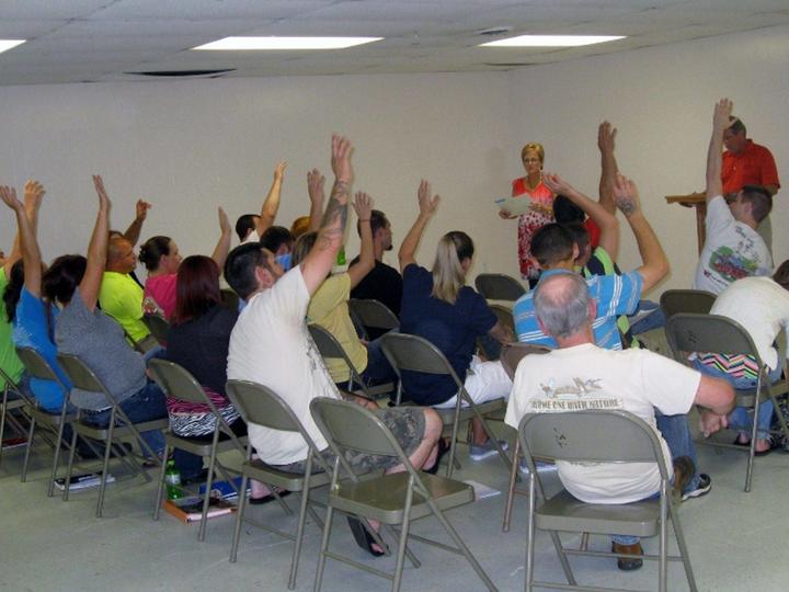 A group of people from court teams being led by an instructor, many with hands raised.
