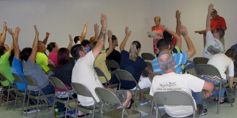 A group of people from court teams being led by an instructor, many with hands raised.